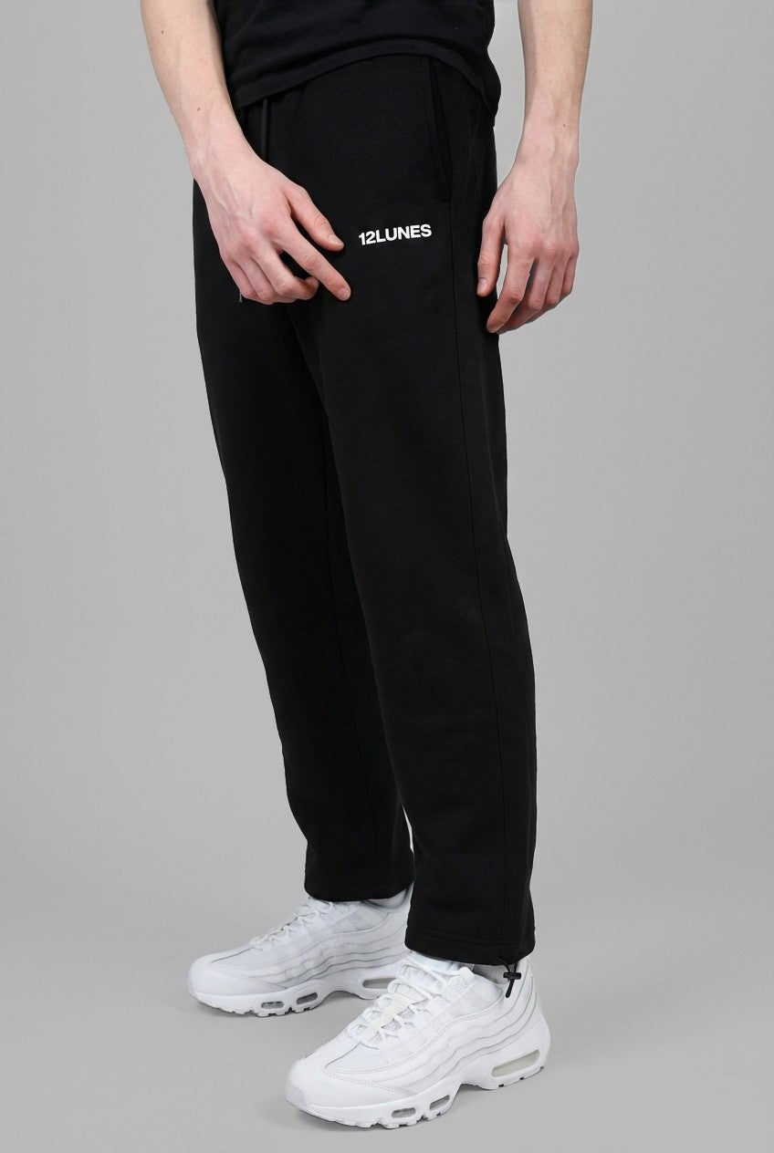 Trackpant Charbon 12LUNES, pantalon de survêtement droit noir porté avec des baskets blanches, vu de trois quarts