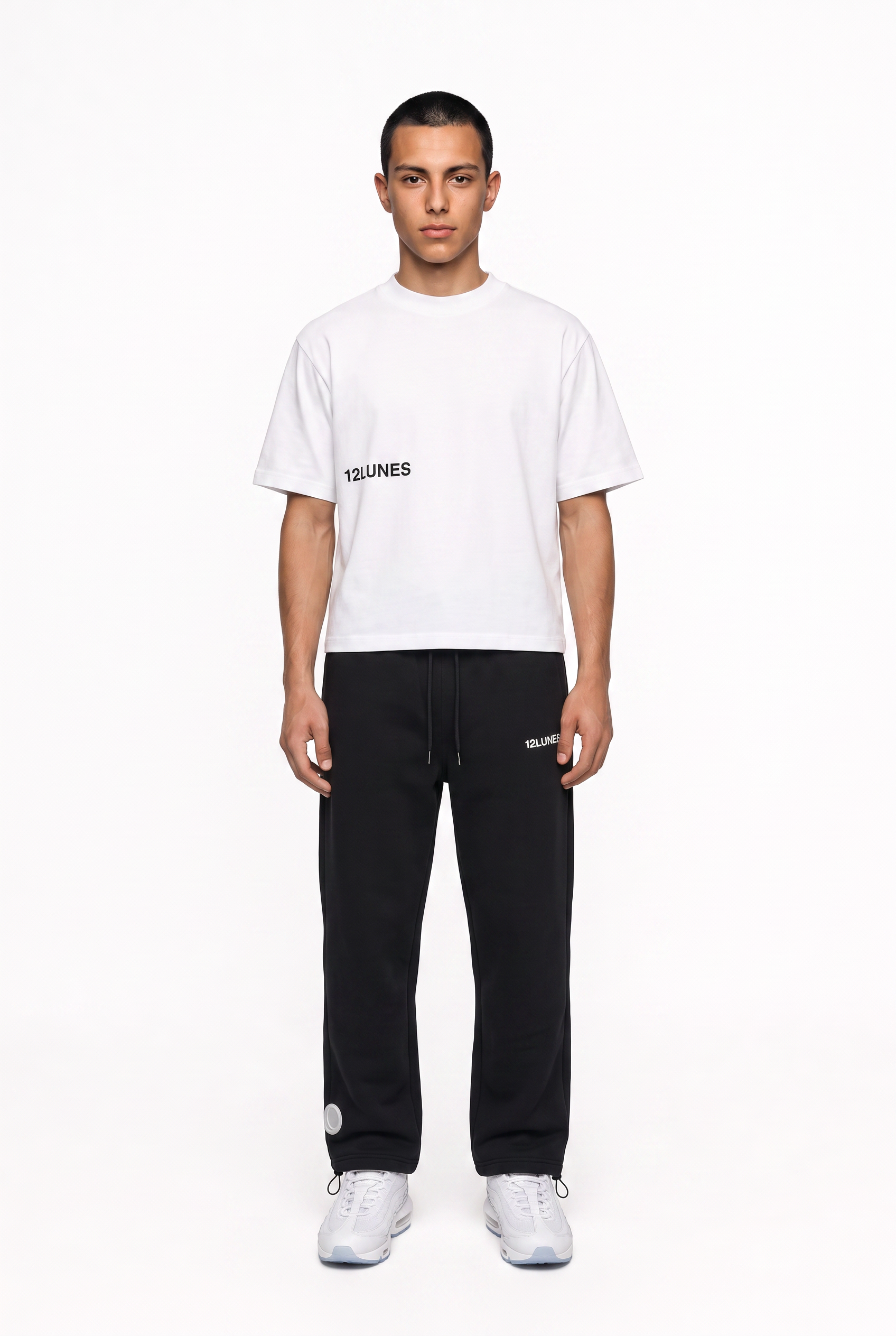 Tee-shirt blanc 12LUNES porté en pied avec le trackpant noir de la gamme ESSENTIALS